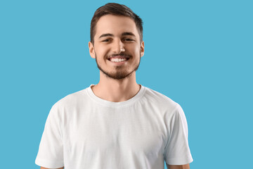 Handsome young man with healthy teeth on blue background. Dental care concept
