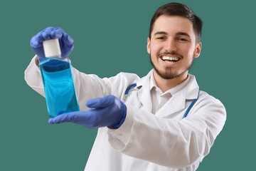 Young male dentist with bottle of mouthwash on green background. Dental care concept