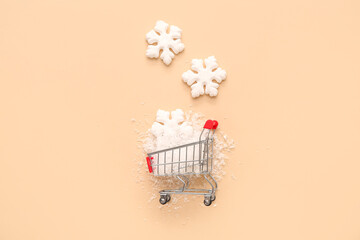 Shopping cart with Christmas decorative snowflakes on beige background
