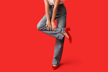Beautiful young Asian woman in stylish jeans on red background, closeup