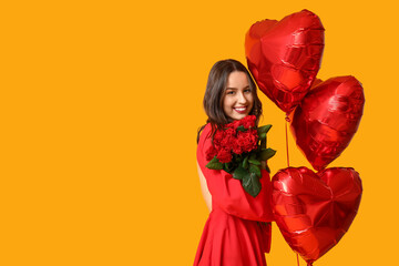 Happy young woman with bouquet of red roses and heart shaped air balloons on yellow background....