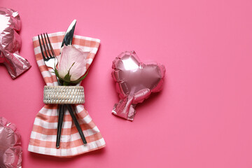 Cutlery with napkin, rose and balloons on pink background. Valentine's Day celebration