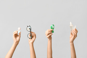Female hands with container for contact lenses, bottle of solution, green ribbon, eyeglasses and...