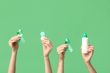 Female hands with ribbons, container for contact lenses and bottle of solution on green background....