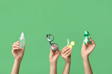 Female hands with ribbon, container for contact lenses, tweezers, eyeglasses and bottle of solution...