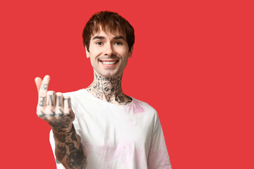 Handsome young man making heart with fingers on red background
