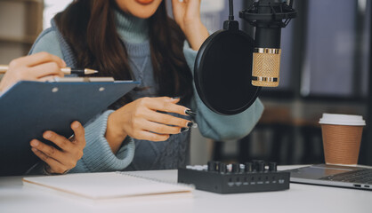 Woman recording a podcast on her laptop computer with headphones and a microscope. Female podcaster making audio podcast from her home studio.
