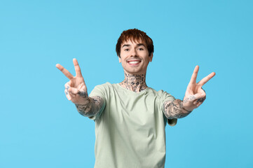 Handsome young man showing victory gesture on blue background