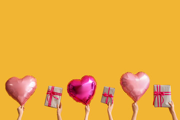 Female hands with gift boxes and heart shaped air balloons on yellow background. Valentine's Day...