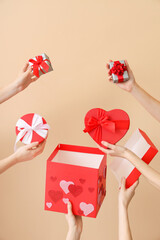 Female hands with gift boxes on beige background. Valentine's Day celebration