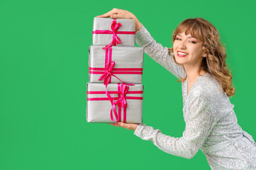 Beautiful young woman with gift boxes on green background. Valentine's Day celebration