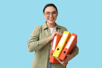 Young businesswoman in eyeglasses with document folders on blue background