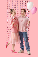 Young couple with balloons and hearts on pink background. Valentine's Day celebration