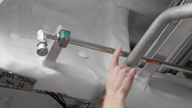 Captain showing Water Mist sprinkler system in ships engine room area, close up