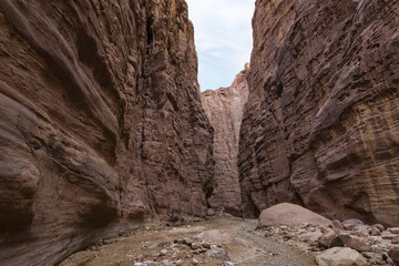 A shallow  stream flows between high mountains at the beginning of the route along the Wadi Numeira hiking trail in Jordan