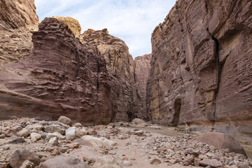 Fototapeta premium High mountains along edges of the gorge at beginning of the walking route along the Wadi Numeira gorge in Jordan