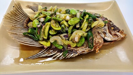 Ikan Gurame Goreng or fried freshwater fish with chilli sauce and vegetable. Serving on plate. Indonesian food and cuisine. Delicious Fried Gouramy, Selected Focus.