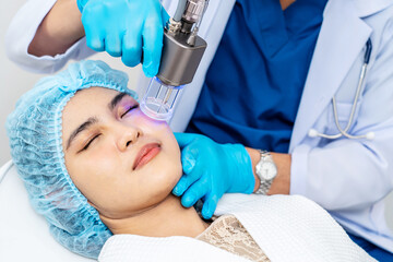 Asian Doctor doing laser on the woman face at beauty clinic. Beautiful woman having facial skin care treatment at beauty clinic, Facial skin care, anti-aging facial rejuvenation.