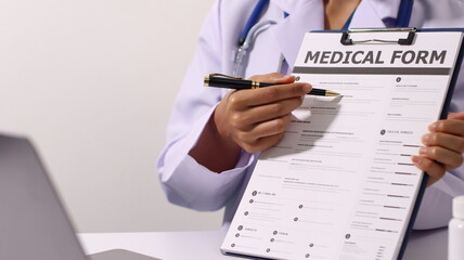 Initial AI illustration of a close-up of a female doctor's hand signing a medical document on a clipboard. and recommending certain medicines to patients on a laptop