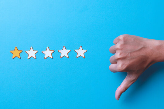 Hand showing thumbs down and one star rating on blue background. Negative feedback concept.