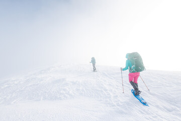 Fototapeta na wymiar climbers climb the mountain. Winter mountaineering. two girls in snowshoes walk through the snow.