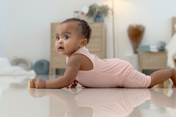Portrait of smiling African cute toddle baby infant kid crawling on floor in bedroom at home. Happy...