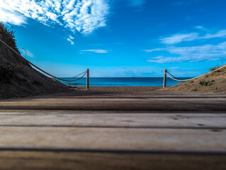 Ground level of wooden boardwalk near blue sea at beach under bright sky on sunny summer day
