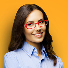 Portrait of cheerfully smiling amazed businesswoman in eye glasses spectacles. Brunette business woman at studio, isolated orange yellow background. Square photo. Ophthalmology.