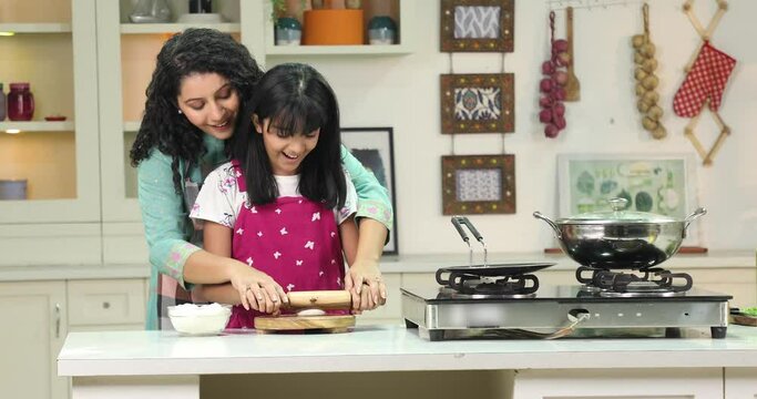 Video of Indian Mother teaching her daughter preparing chapati in a kitchen
