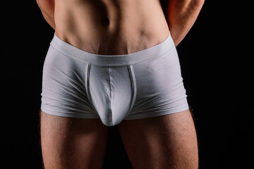 Belly and hips of a young Caucasian sporty man in white trunks underpants, close-up studio