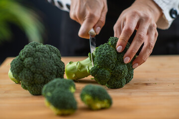 Cutting fresh organic broccoli, a superfood rich in vitamin K, vitamin C, folic acid, potassium,...