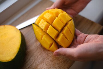 man cutting organic mango into cubes close-up of hands, healthy eating concept