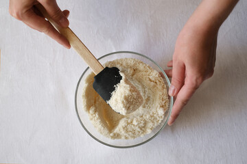 female cook stirring almond flour in a glass plate top view - Powered by Adobe