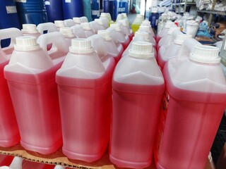 lots of white jerry cans filled with hand soap and sanitizer liquid in warehouse	