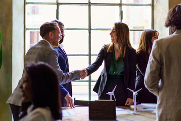 Two business professionals greet each other with a handshake, symbolizing a successful agreement in a vibrant office atmosphere.