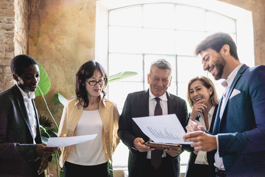 Diverse corporate team engaging in a strategic meeting, emphasizing collaboration and multicultural interaction in a bright office.
