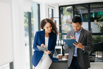 Businesswomen work and discuss their business plans. A Human employee explains and shows her colleague the results paper