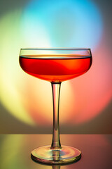 Flat champagne glass on a bright multicolored background. Drink in a bright festive glass. Colorful light is refracted in glass.