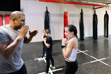 Horizontal photo children with their teacher in a boxing school warming up. Sport concept.