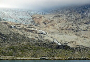 the sermeq glacier and rocky sprires  at the end of the tasermuit fjord on a sunny summer day near...
