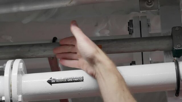 Captains hand showing fuel line in ceiling of ships engine room area