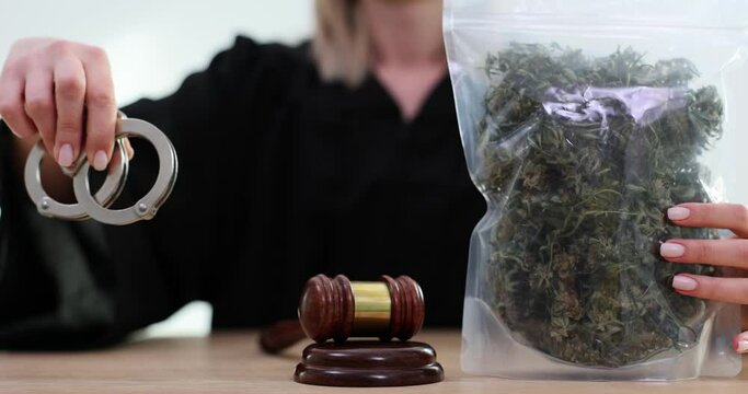 Judge hands out bag of marijuana and handcuffs near gavel in courtroom 4k movie slow motion