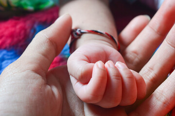 Close up of a newborn baby's hand being held by the mother as a sign of affection