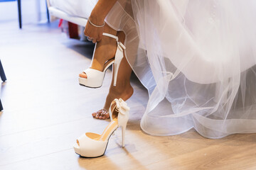 Detail of a bride in her wedding dress before the ceremony putting on her high heels