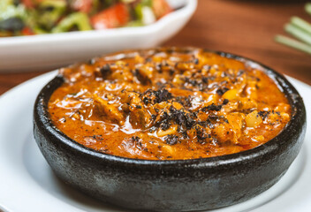 Thai spicy chili sauce with pork in black bowl on wooden table