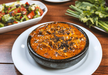 Thai spicy chili sauce with pork in black bowl on wooden table
