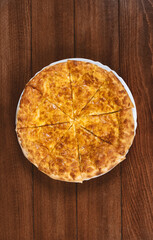 pie with cheese on a white plate on a wooden background