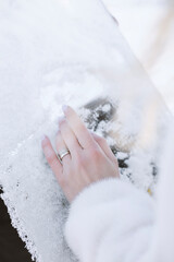 Close up of a woman's hand holding a wedding ring in the snow