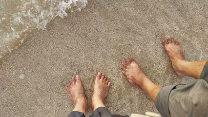 A pair of feet of husband and wife on the beach sand. Romantic and simple holiday background...