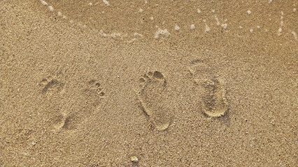 Fototapeta na wymiar Footprints of a husband and wife on the white sand of the beach. Simple romantic holiday background concept